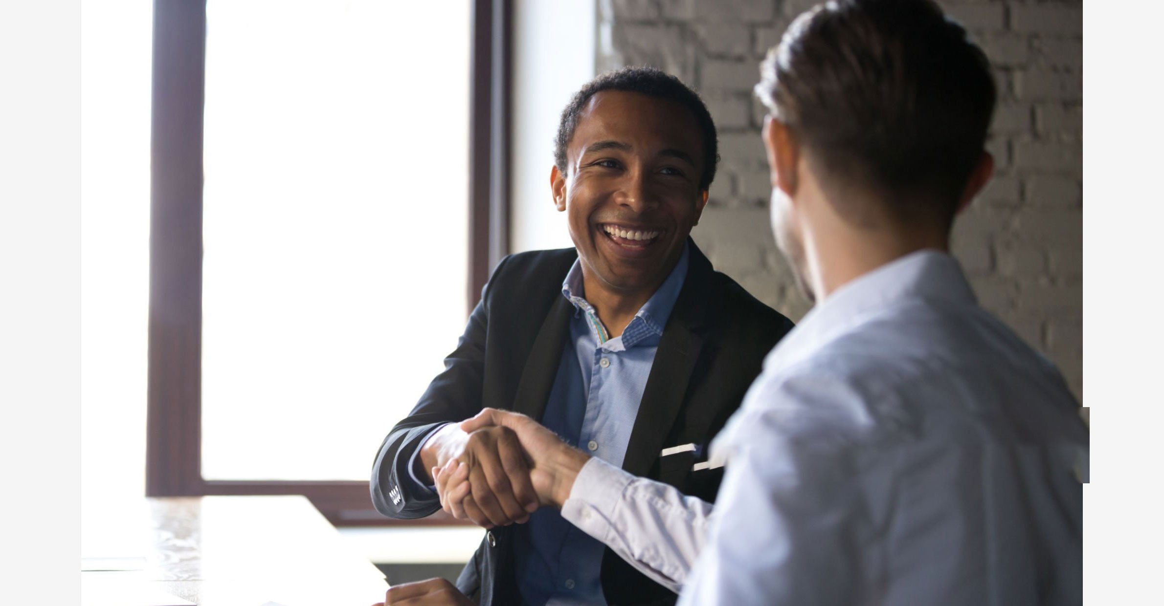 two men shaking hands at table